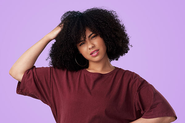 Confused woman scratching her head and looking at camera 